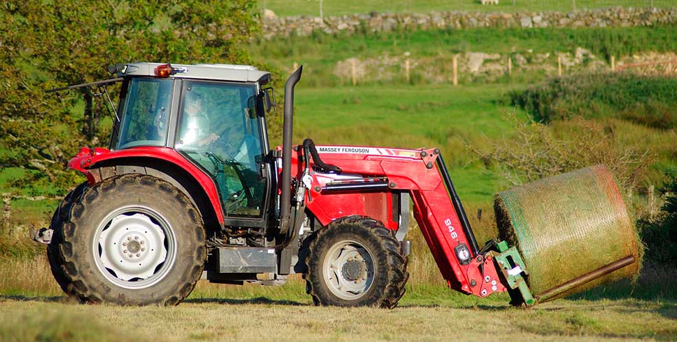 Un tractor en el campo enrollando heno