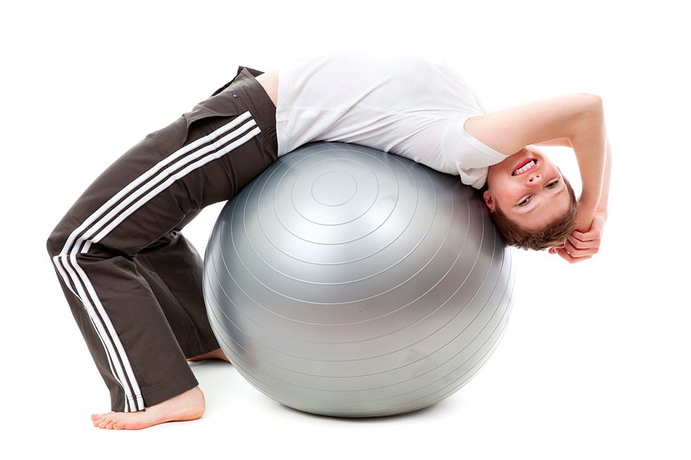 una mujer practica ejercicio físico sobre un balón de fitness