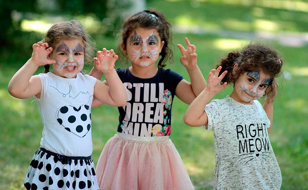 Tres niñas pequeñas juegan con las caras pintadas