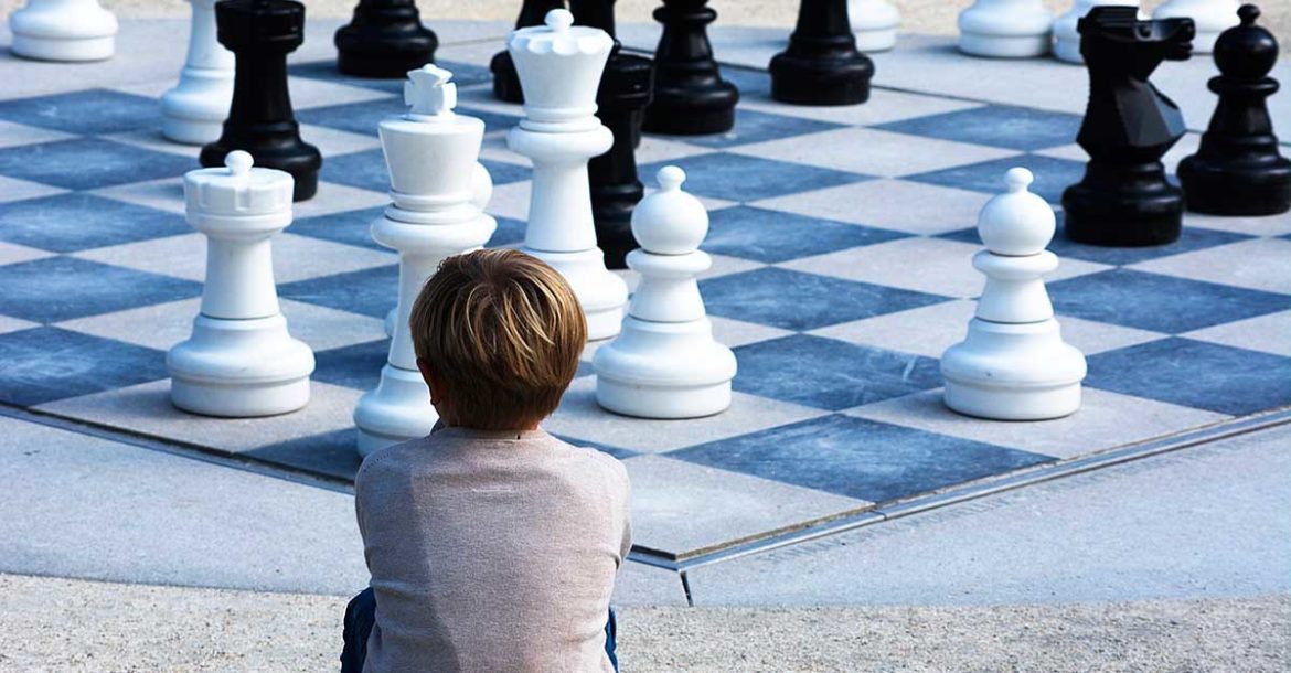 Un niño de epaldas contwmpla un tablero gigante de ajedrez