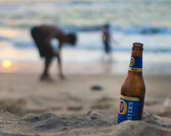 Una botella de cerveza en la playa y unos niños al fondo