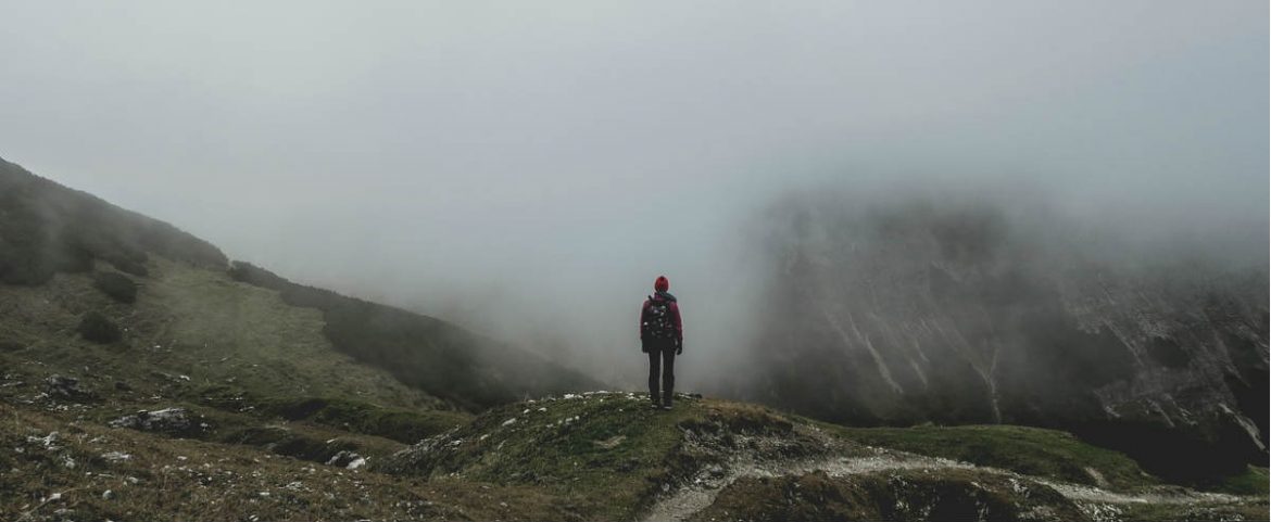 Un hombre asomado a un valle con niebla