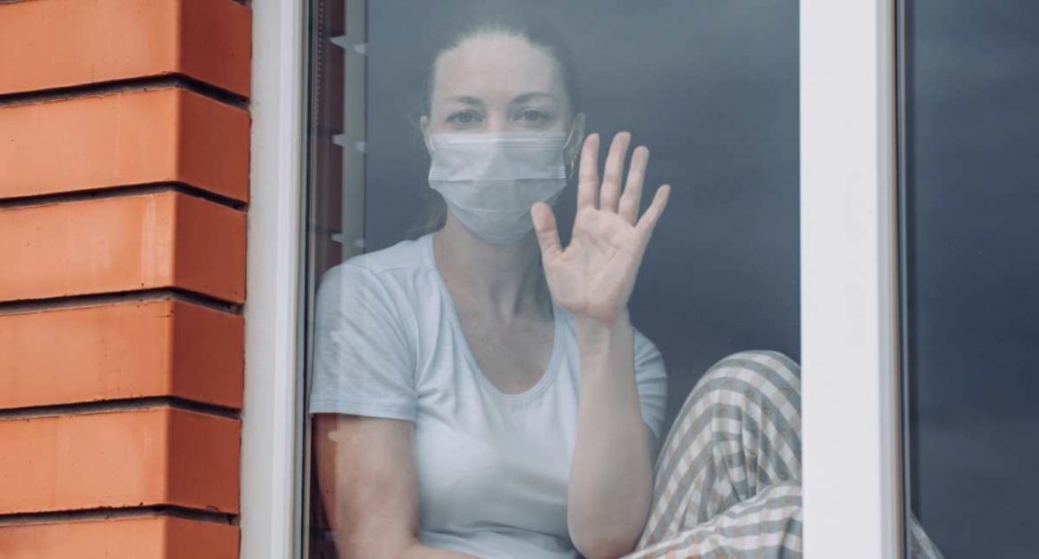 Una mujer con mascarilla en una ventana