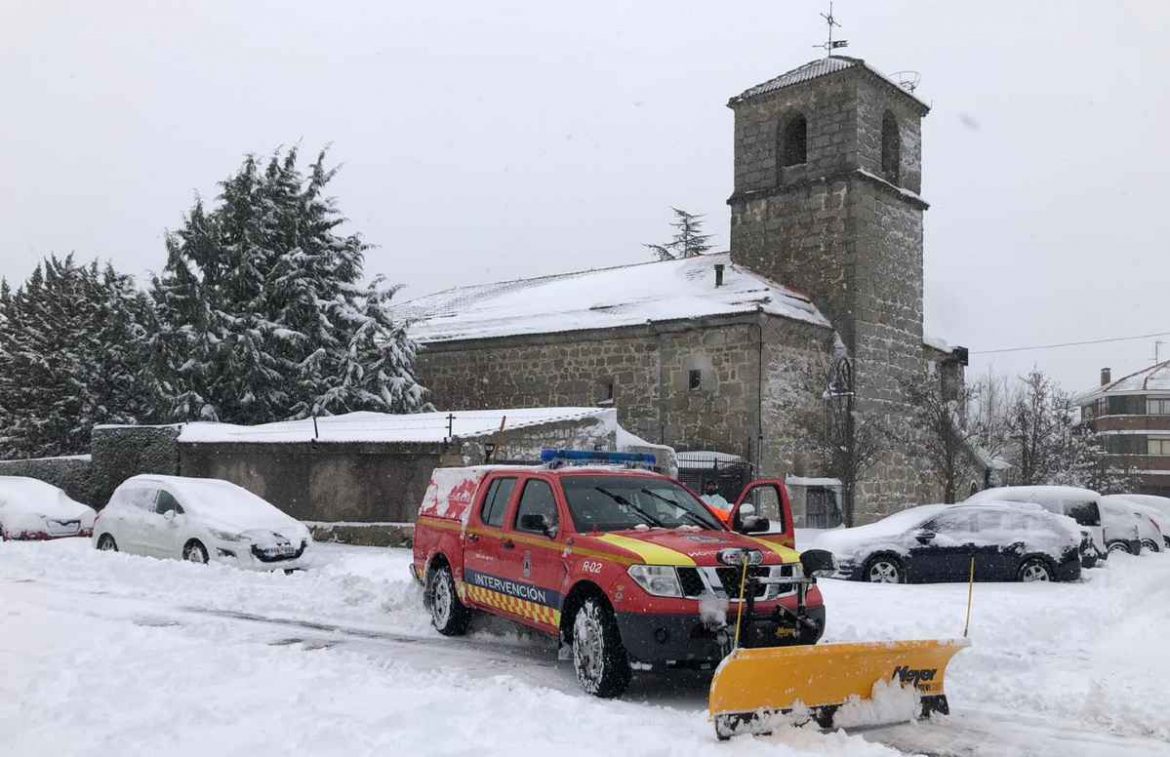 Un vehículo de Protección civil durante la nevada de Filomena con la iglesia de Moralzarzal al fondo