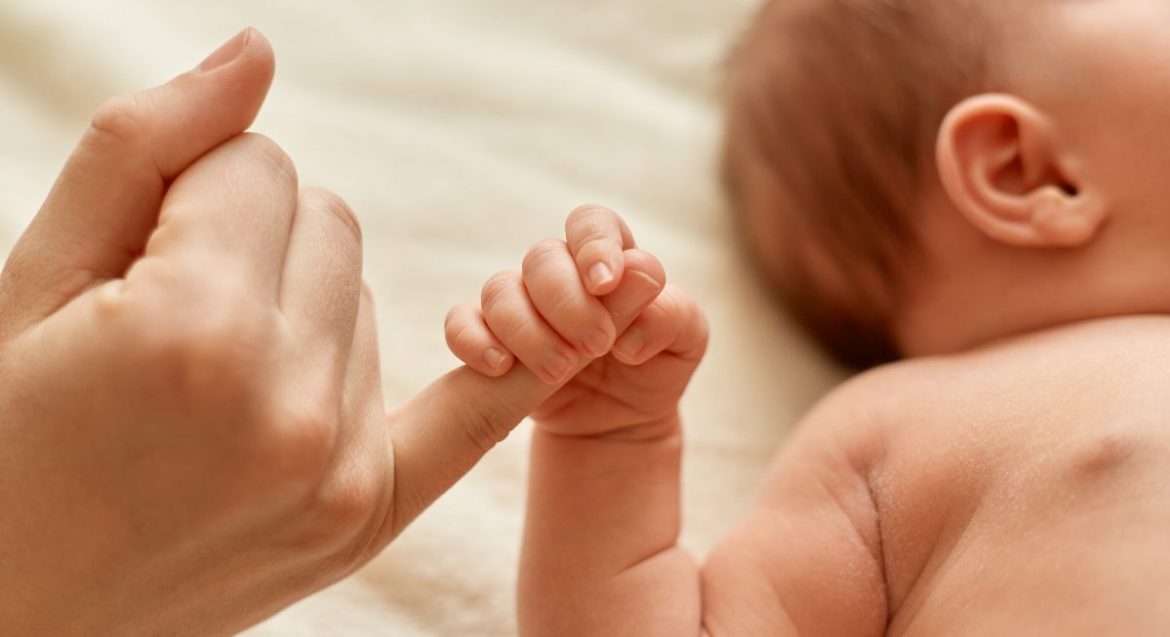 Un bebé aprieta el dedo de un adulto