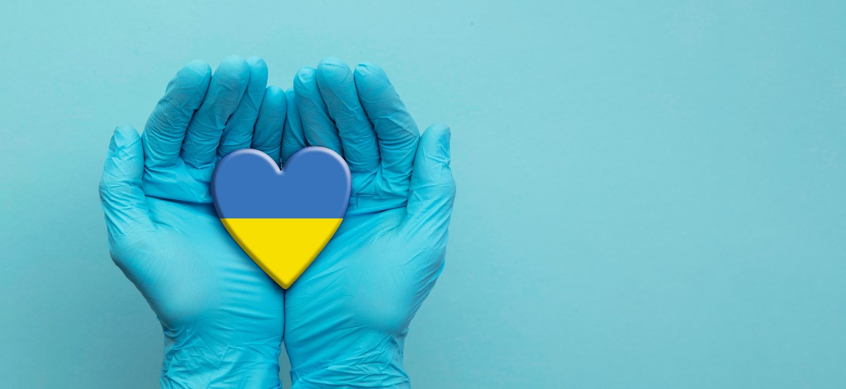 Unas manos enguantadas sujetan un corazón con la bandera de Ucrania