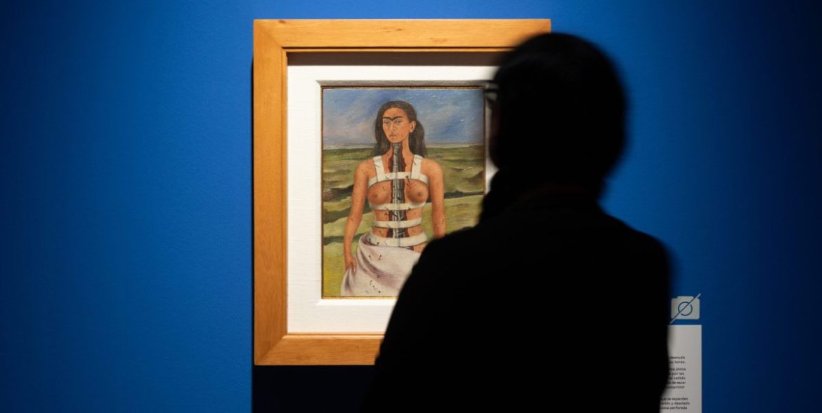 Silueta de una persona mirando un autorretrato de Frida Khalo