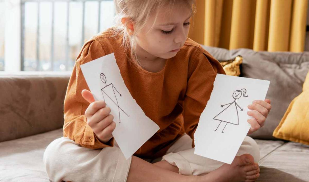 Una niña sujeta un papel roto con el dibujo de su madre y padre